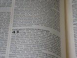 A close-up view of an open book showing a page filled with text. The text is written in a serif font, with some numbers written in a larger, bold font. The content seems to be divided into sections or paragraphs with headings.