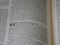 A close-up view of an open book showing a page filled with text. The text is written in a serif font, with some numbers written in a larger, bold font. The content seems to be divided into sections or paragraphs with headings.