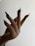 A hand with long, pointed black nails extends upward against a light background. The fingers are elegantly splayed, showcasing the dramatic nail design.