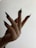 A hand with long, pointed black nails extends upward against a light background. The fingers are elegantly splayed, showcasing the dramatic nail design.