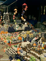 Local artisans at a vibrant market stall displaying colorful ceramics and fresh produce.