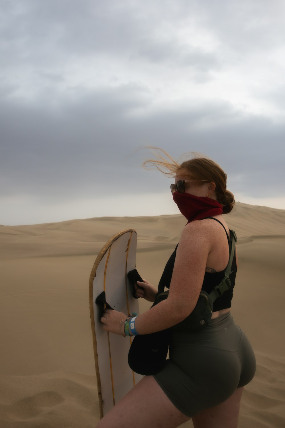 a woman holding a surfboard in the desert