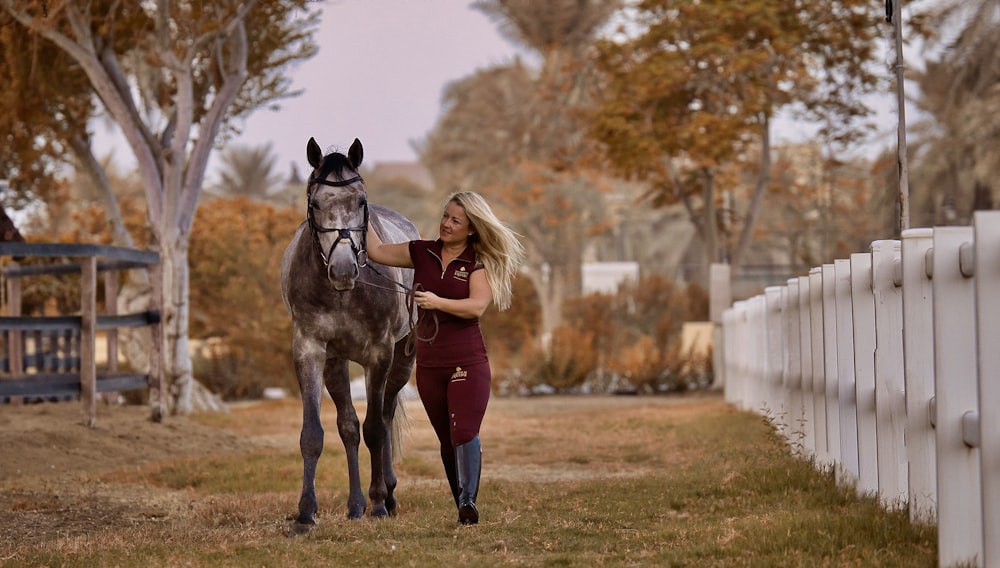 a woman standing next to a horse in a field