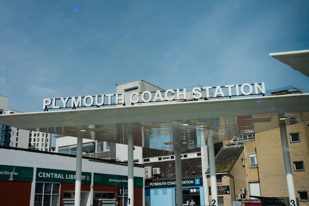 a sign that reads plymouth coach station above a building