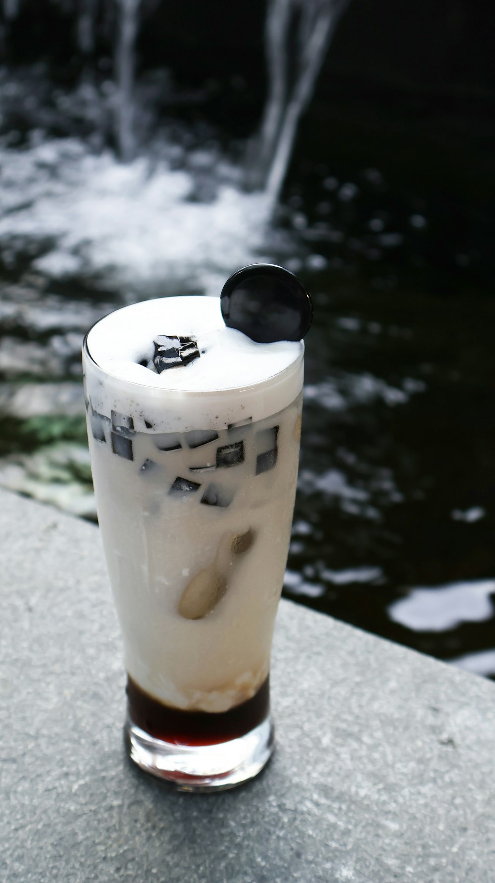 a drink sitting on top of a table next to a waterfall