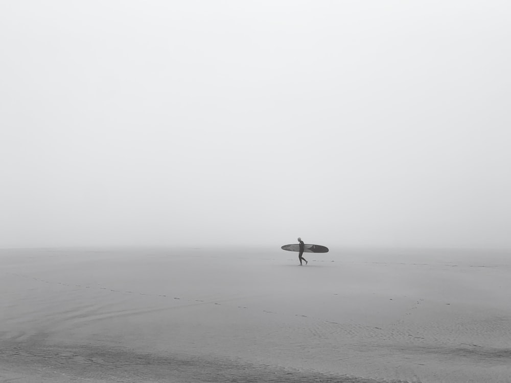 a person holding a surfboard on a foggy beach