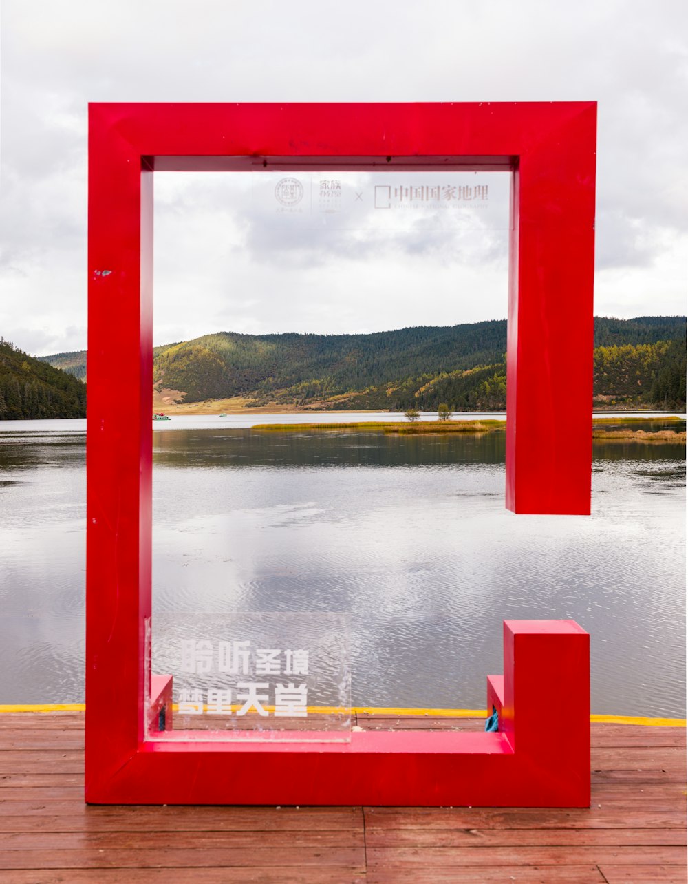 a red frame sitting on top of a wooden pier