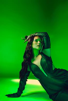 Stephie Graff posing in a stylish neon emerald green outfit against a dark cinematic background with subtle glow effects.