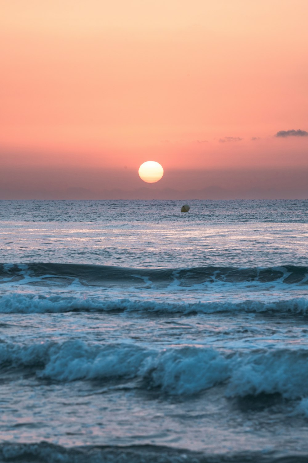 the sun is setting over the ocean with waves