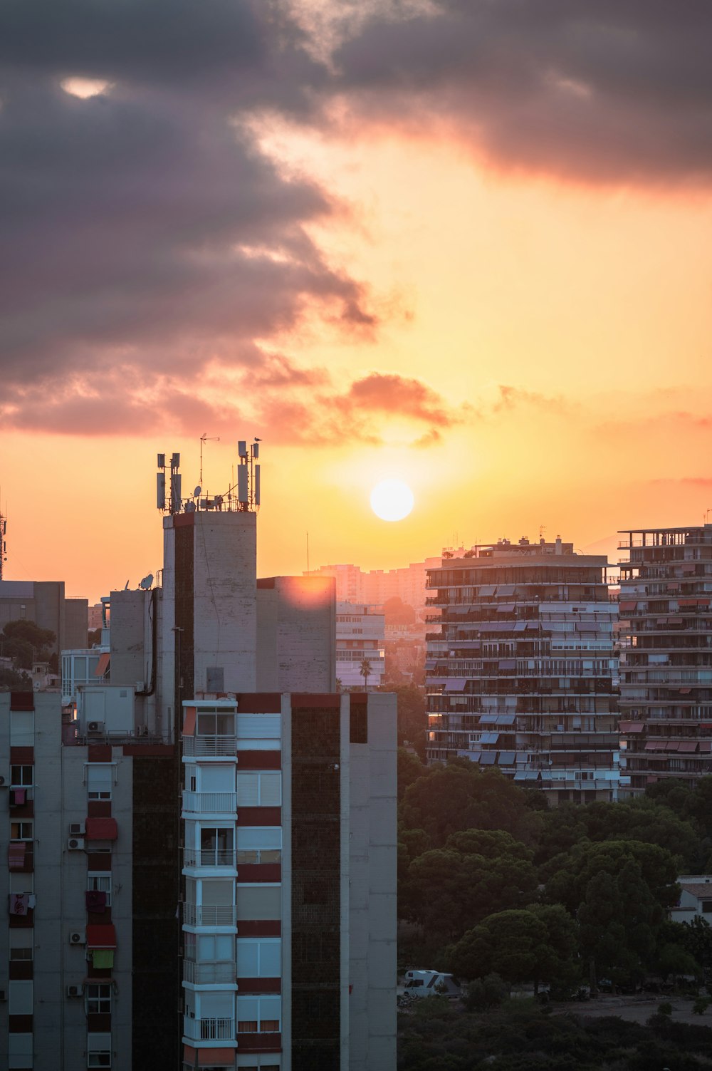 the sun is setting over a city with tall buildings