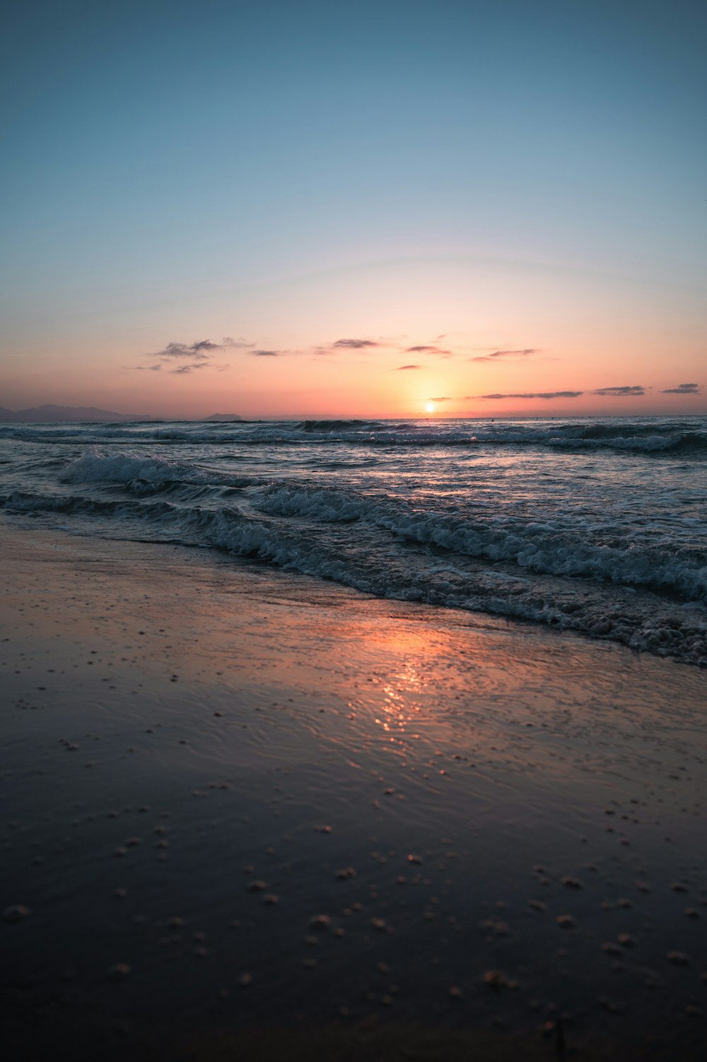 the sun is setting over the water at the beach