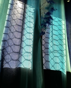 Sunlight filtering through a curtain of hanging beads and feathers.