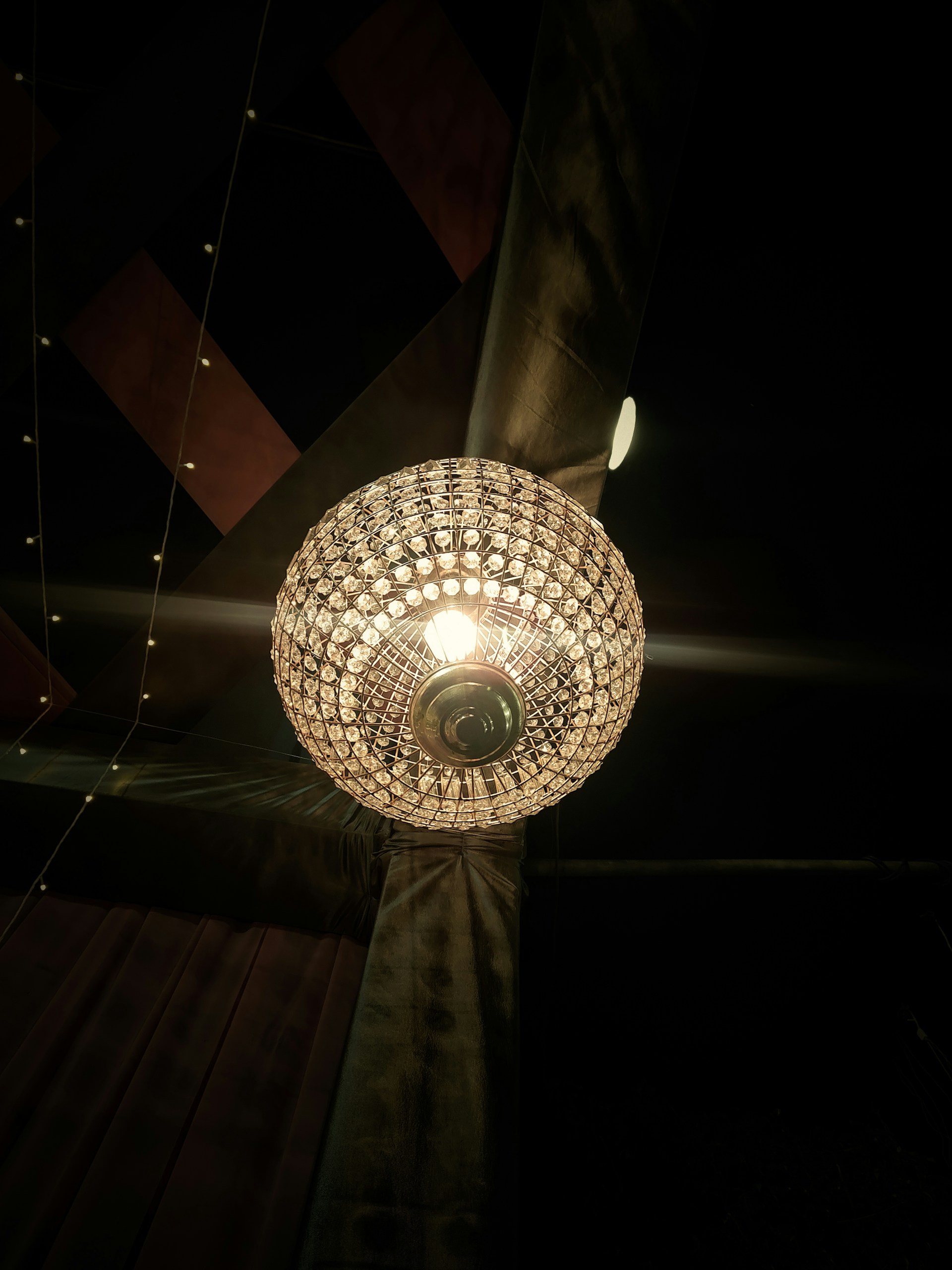 A sculptural chandelier from kld lighting casting warm, intricate shadows over a modern living room.