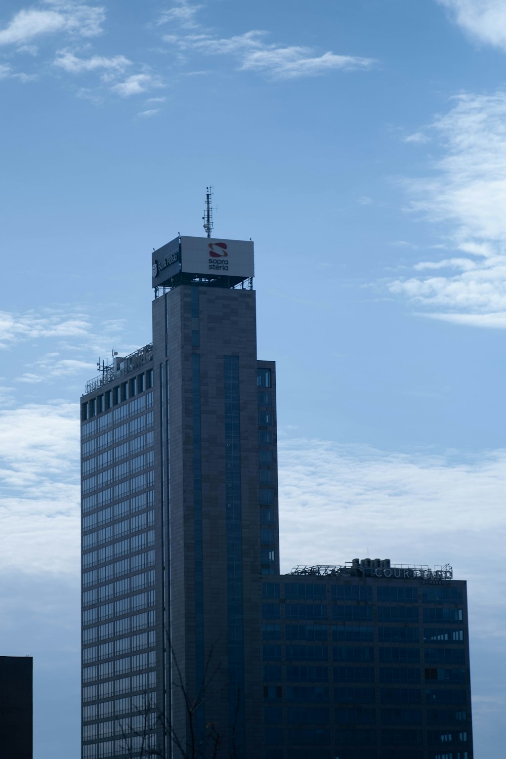 ein hohes Gebäude mit einem Fernsehturm auf der Spitze