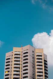 A sleek architectural rendering of a modern multifamily building under construction against a clear sky.
