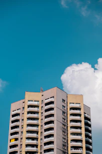 A sleek architectural rendering of a modern multifamily building under construction against a clear sky.
