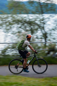 a man riding a bike down a street next to a lake