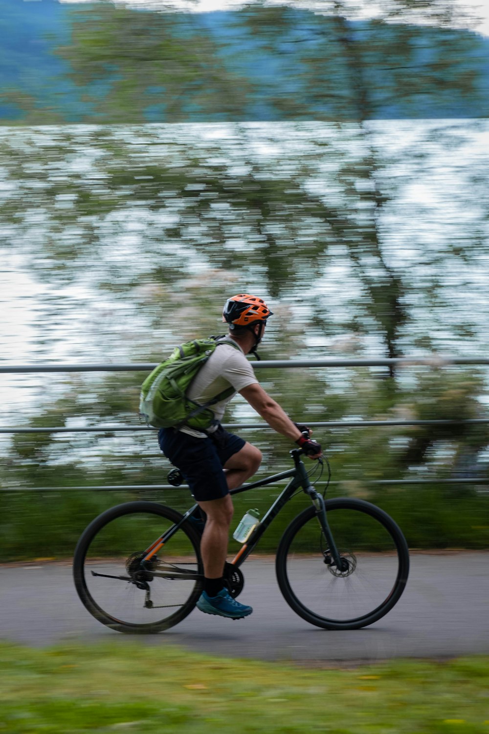 a man riding a bike down a street next to a lake