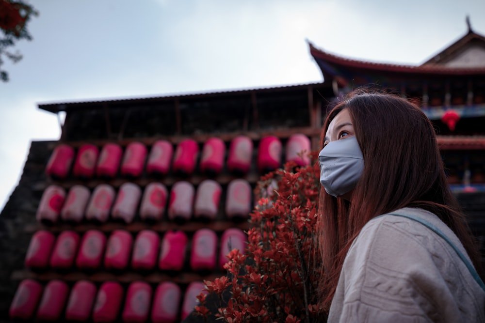 a woman wearing a face mask standing in front of a building