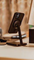 A stylish phone stand holding a smartphone, set against a soft, blurred background.