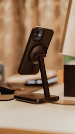 A sleek modern smartphone on a wooden desk with a blurred background.