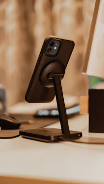 Close-up of a sleek black leather phone case with brushed gold accents resting on a modern desk.