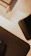 A Quad Lock branded device holder is situated on a desk. The image includes parts of a black mouse pad and edges of a wooden desk or structure, with a minimalist and organized appearance.