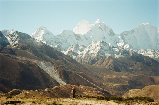 A vibrant photo of a hiker overlooking Valdez’s rugged coastline with snow-capped mountains in the background.