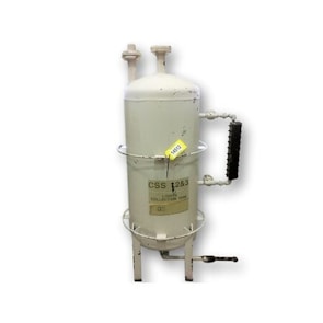 A cylindrical metal tank with a rounded top, featuring two vertical pipes protruding from the top. There is a horizontal handle on one side with black grips, and a label indicating 'CSS 223 & LIGHT COLLECTION TANK'. The tank is elevated on short legs, and its surface shows signs of wear and slight rusting.