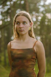 A model wearing a cozy, earth-toned outfit paired with delicate earrings in an outdoor setting.