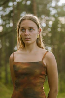 A model wearing a cozy, earth-toned outfit paired with delicate earrings in an outdoor setting.