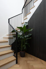 Elegant black metal railing with wooden handrail on a staircase landing.