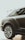 A sleek, black luxury car is parked indoors, showcasing its prominent and stylized alloy wheel. The glossy finish and elegant design reflect modern automotive craftsmanship. The window reflects palm tree silhouettes, adding a touch of sophistication.