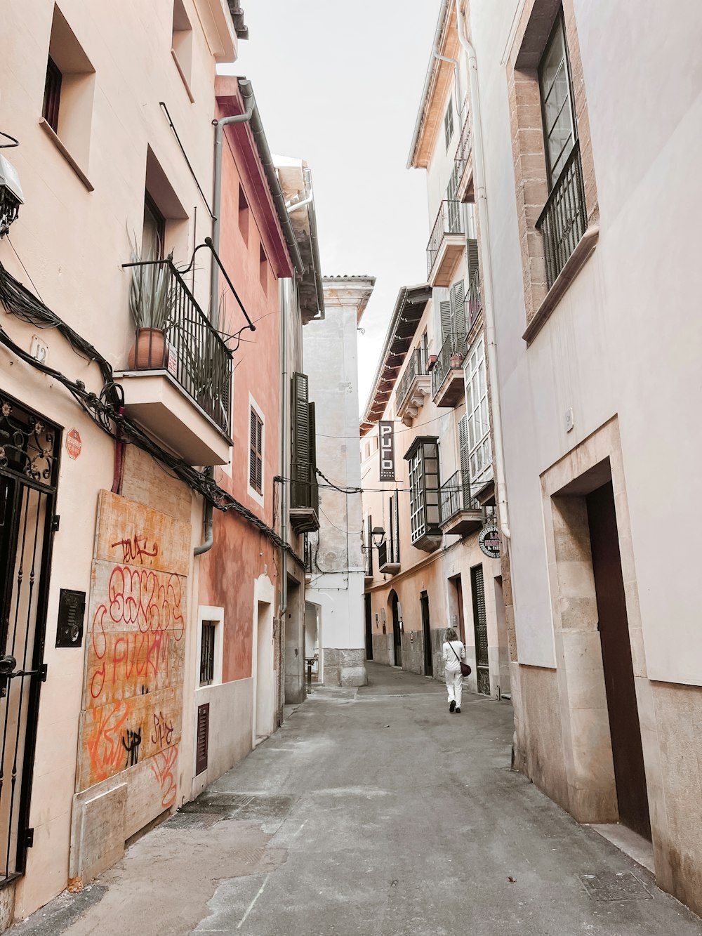 a narrow city street with graffiti on the buildings