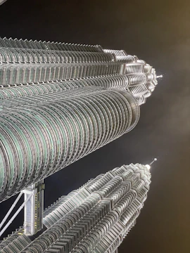 A stunning aerial view of BPTP Skynest's twin towers piercing the Faridabad skyline at sunset.