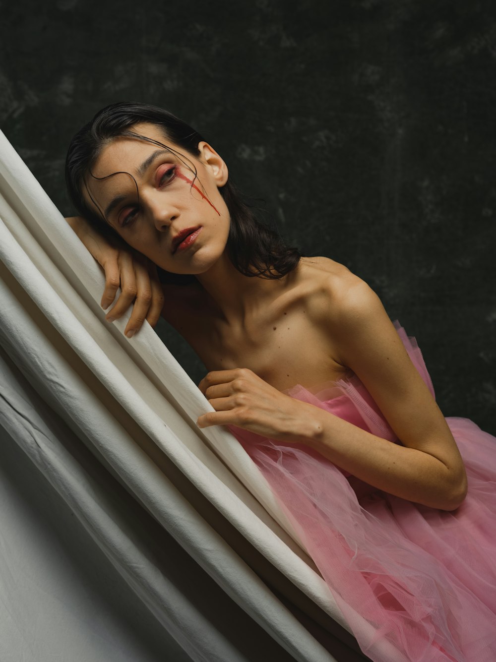 a woman in a pink dress leaning against a wall