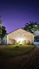 Historic stone lodge building illuminated softly at dusk, surrounded by mature trees.