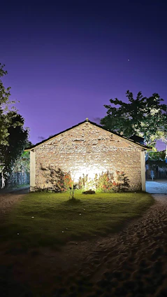 Historic stone lodge building bathed in soft evening light, surrounded by tall trees in Montérégie.