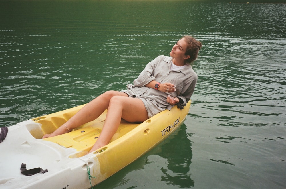 a woman sitting on a yellow kayak in the water