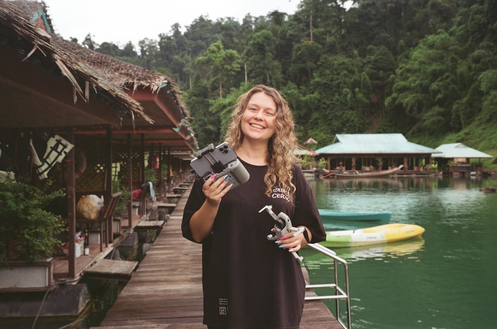 a woman standing on a dock holding a camera