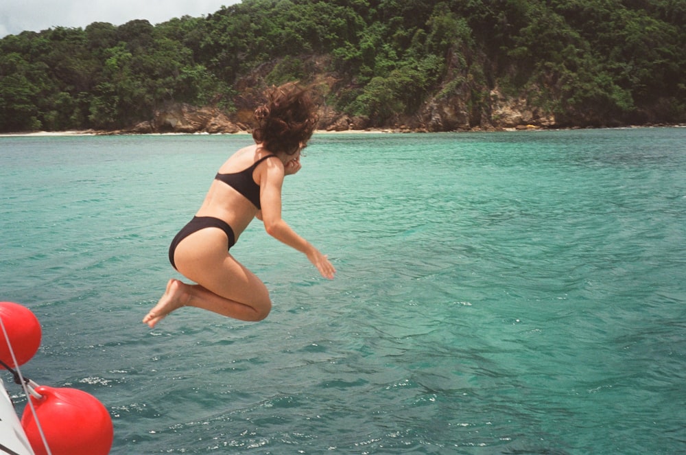 a woman jumping off a boat into the ocean