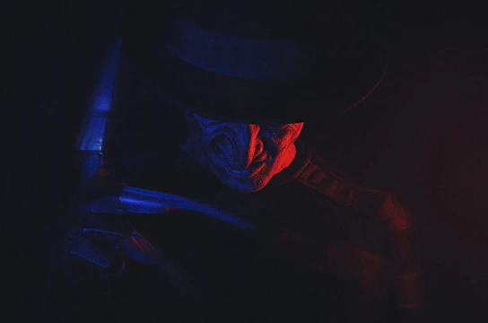 A sinister clown magician with glowing eyes performing dark tricks under a flickering carnival tent.
