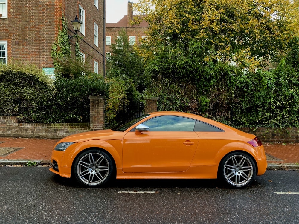 an orange sports car parked on the side of the road