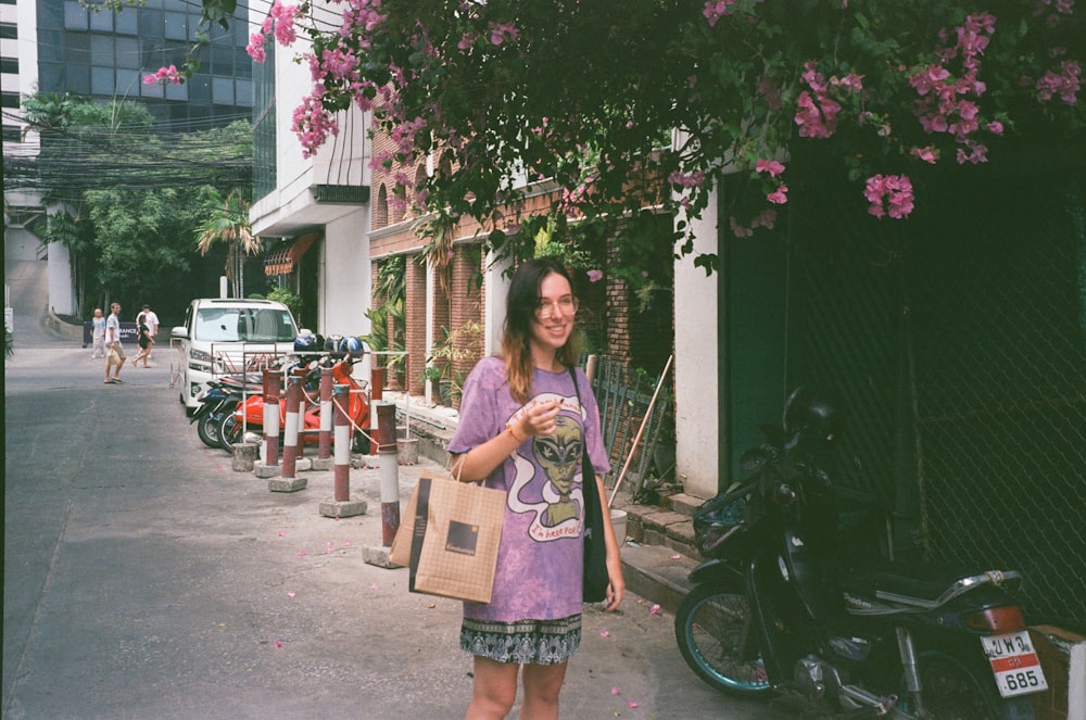 a woman standing on a street holding a bag