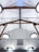A modern ceiling design featuring wooden beams and multiple circular light fixtures. The ceiling has a high pitch with a skylight at the top center, and the beams form a triangular pattern. Several electrical wires and cables are arranged in a neat and organized manner.