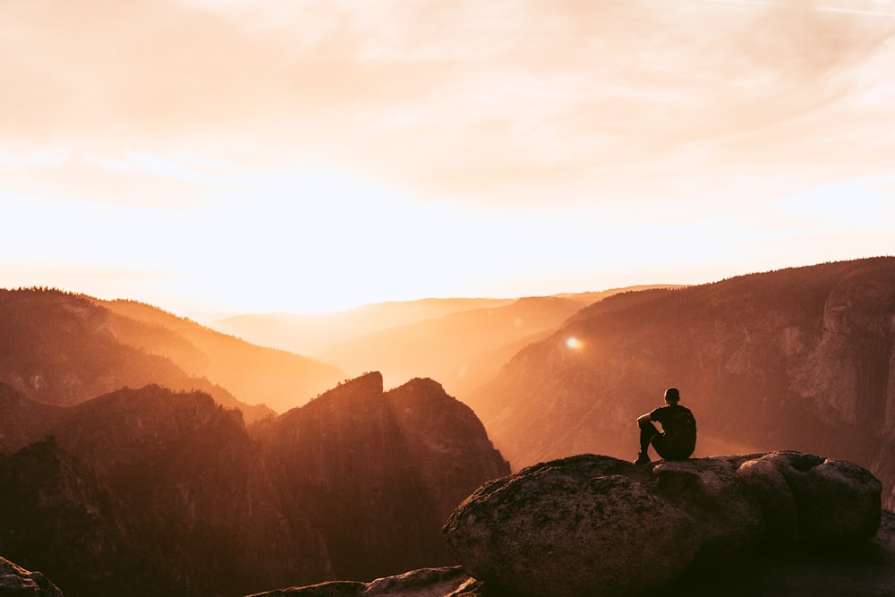 a man sitting on top of a large rock