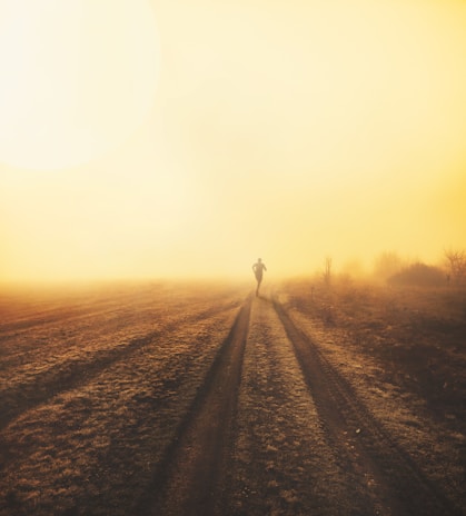 Trail runner crossing a rugged mountain path at sunrise, showcasing endurance and focus.