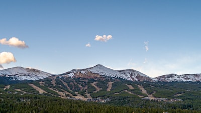 A scenic view of a snowy mountain ski resort with a family skiing together under a clear blue sky.