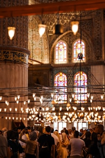 A vibrant photo of the congregation gathered in the main sanctuary, bathed in warm purple and gold light.