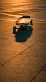 An electric longboard resting against a graffiti-covered wall, bathed in golden afternoon light.
